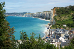 An illustrative photo of houses on a cliff by the sea.