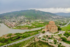 An illustrative photo of a town near a body of water and a mountain.
