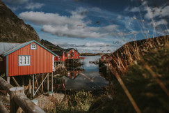 An illustrative photo of three red houses near a body of water.