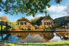 An illustrative photo of two brick houses near a river.