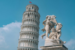 An illustrative photo of the Tower of Pisa and a statue next to it.