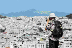 An illustrative photo of a man standing on top of a hill taking a picture.