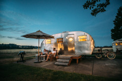 An illustrative photo of people sitting in front of rv trailer.