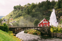 An illustrative photo of a red house sitting on top of a lush green hillside.