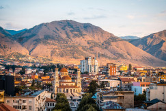 An illustrative photo of a city with mountains in the background.