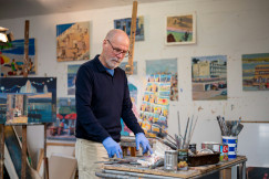 An illustrative photo of a man in a blue shirt painting.