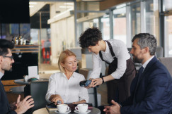 An illustrative photo of a waiter serving a table with three people.