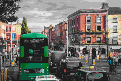 An illustrative photo of a green bus and cars on a city road.