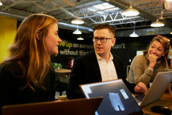 An illustrative photo of three people talking in the office.