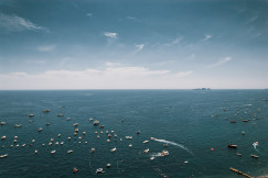 An illustrative photo of white boats on a sea under blue sky.