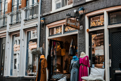 Street view of a small clothing boutique with dresses displayed outside.