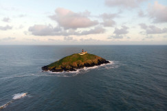 An illustrative photo of a green and brown island under white clouds.