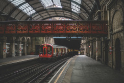 An illustrative photo of a red train traveling inside a train station.