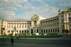 An illustrative photo of people walking near white concrete building during daytime.