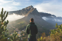 An illustrative photo of a man standing in front of mountain.