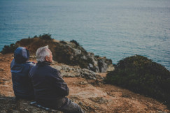 An illustrative photo of two person sitting on a rock.