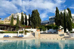 An illustrative photo of white buildings near a swimming pool.