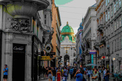 An illustrative photo of people walking in a street between buildings.