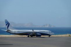 An illustrative photo of a white and blue airplane near a body of water.