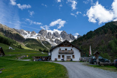 An illustrative photo of a white house beside a road in the mountains.