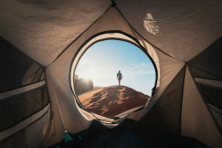 An illustrative photo of a man standing in a tent.