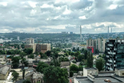 An illustrative photo of city buildings under white clouds.