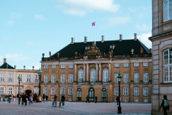 An illustrative photo of a group of people walking around a large building.