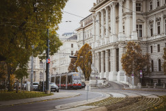 An illustrative photo of a tram going near a big white building.