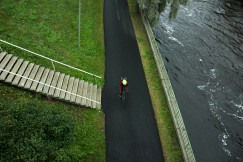 An illustrative photo of a man cycling near body of water.