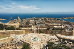 An illustrative photo of city buildings near a body of water during daytime.