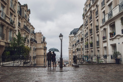 An illustrative photo of people with an umbrella standing between buildings.