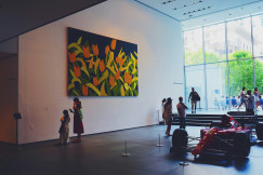 An illustrative photo of a group of people standing in front of a painting.
