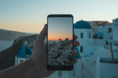 An illustrative photo of a person holding black smartphone taking photo of city.