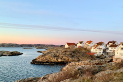 An illustrative photo of houses on a rocky coast near a body of water.