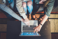 three person pointing the silver laptop compute