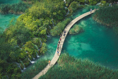 An illustrative photo of people walking on a pathway over a river.