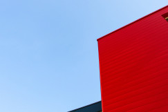 Colour photograph of a grey and red building against a blue sky