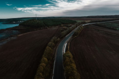 An aerial view of a road between forest and body of water