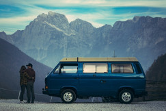 A couple standing next to a van with a mountain view