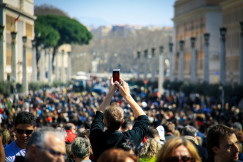A person taking a picture with a phone in a middle of a crowd