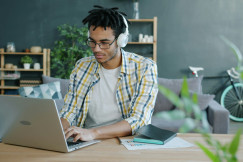 Man with headphones working on laptop at home office 