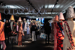 Visitors walking through a textile exhibition space featuring mannequins dressed in innovative knitwear designs and materials.