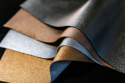 Close-up of layered leather sheets in various colours and textures with a black background.