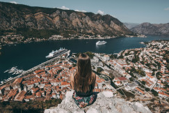 woman-sitting-on-top-of-cliff-facing-buildings