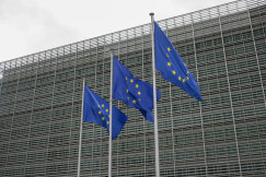 Three European flags flying in front of a building photo.
