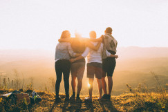 four-person-hands-wrap-around-shoulders-while-looking-at-sunset