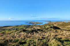 a-grassy-hill-with-a-body-of-water-in-the-distance