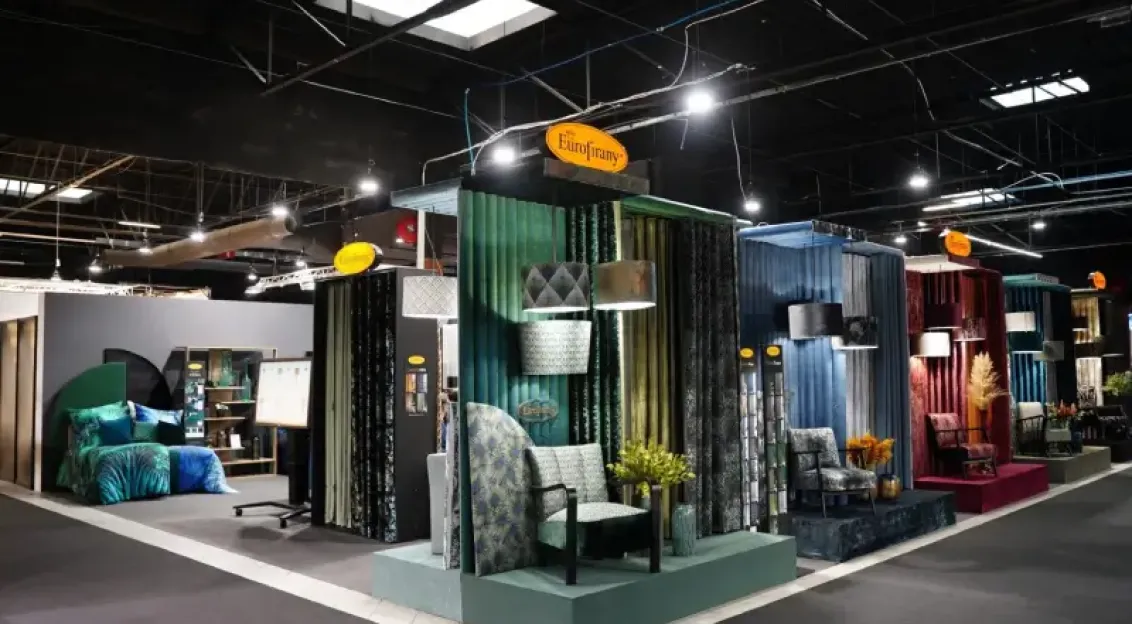 Exhibition stand showcasing interior textiles, fabrics and furniture setups at a trade fair.
