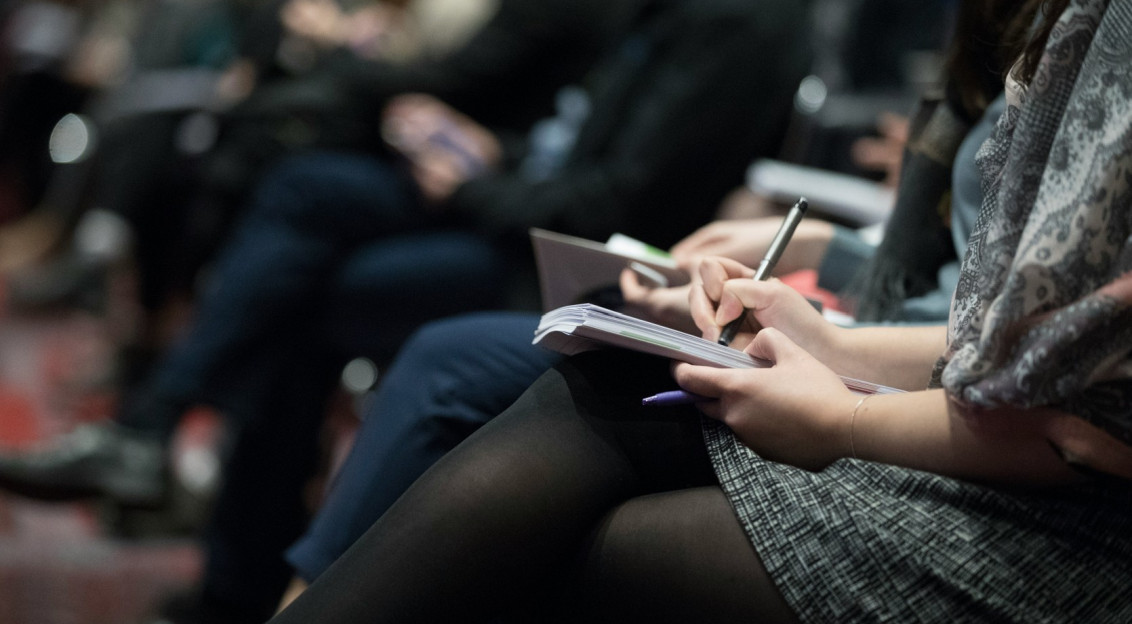 Audience members taking notes during a conference.
