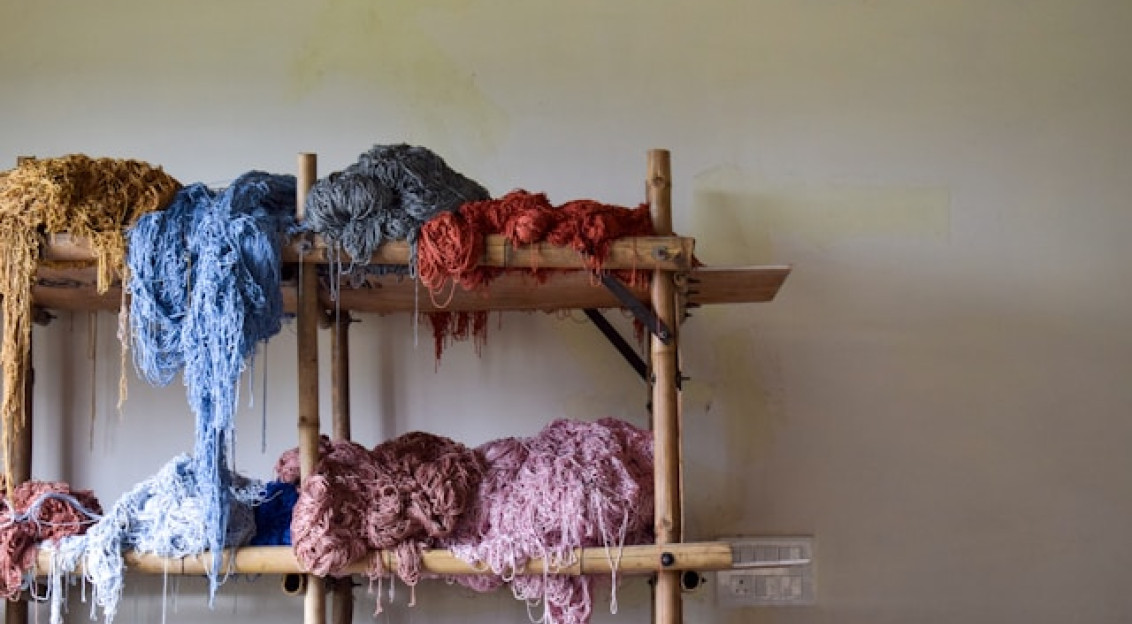 Bunches of colorful yarn on a wooden shelf.